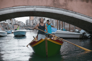 Rema um barco veneziano tradicional com um guia local
