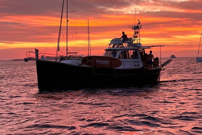 navega hacia la puesta de sol en un llaüt balear privado