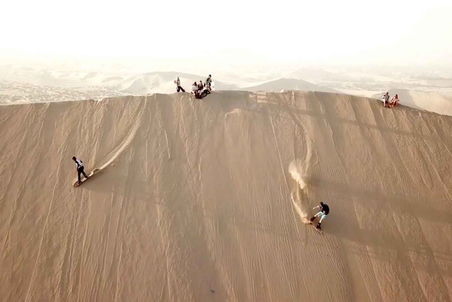 Sandboarden in de Ica-woestijn bij zonsondergang